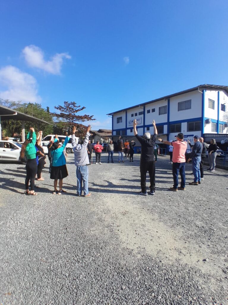 Grupo de pessoas no pátio da Acevali fazem ginástica.