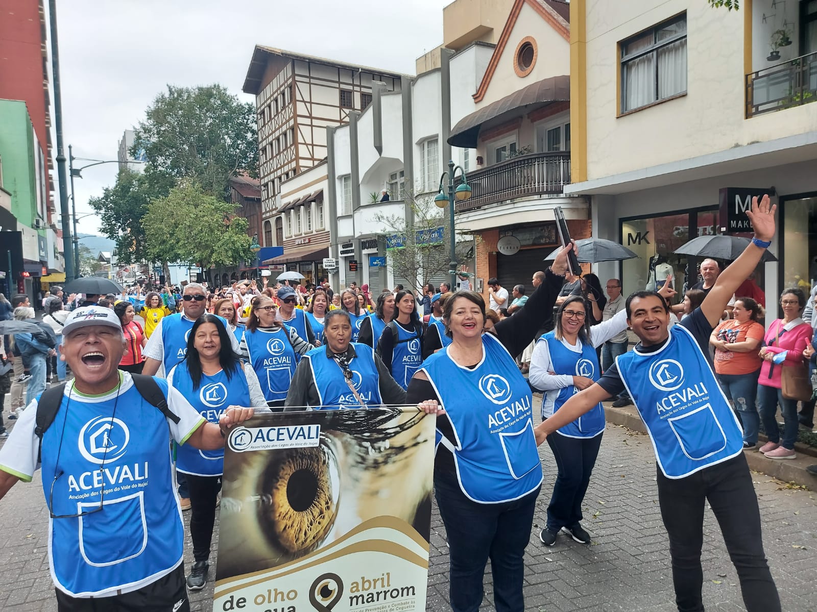 Grupo de pessoas vestindo coleto azul da Acevali em um desfile em Blumenau.